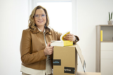 Foto von Mag. Stefanie Steiner mit einem Paket und Steuerunterlagen